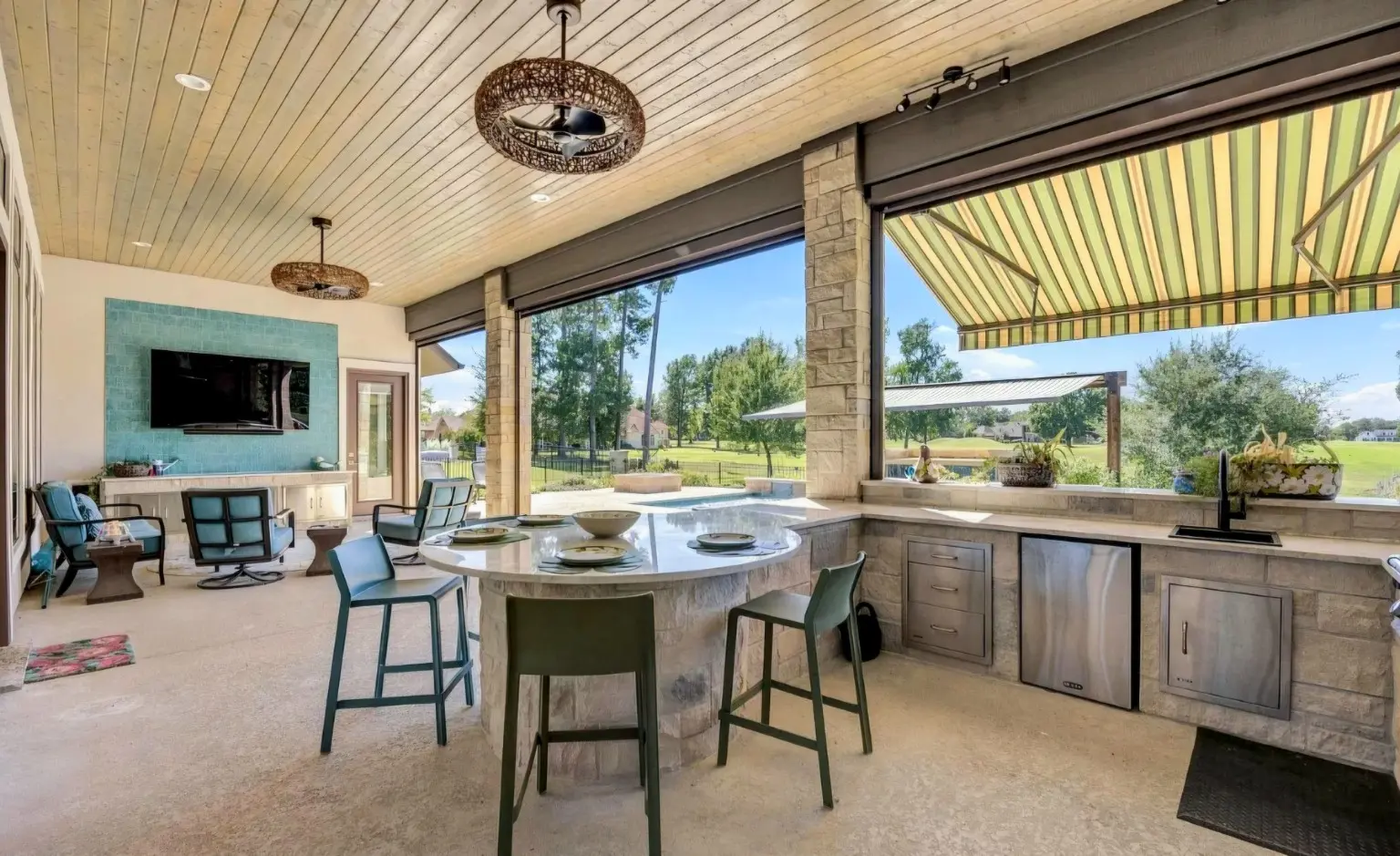 Covered outdoor kitchen with a dining island and seating from the King Pools project archive